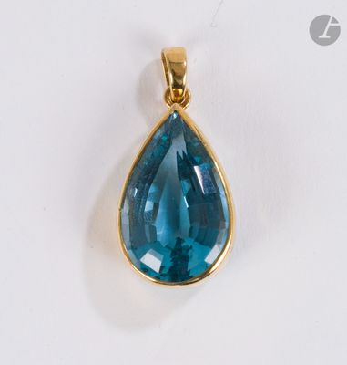 un gros plan d'un pendentif en topaze bleue sur une surface blanche