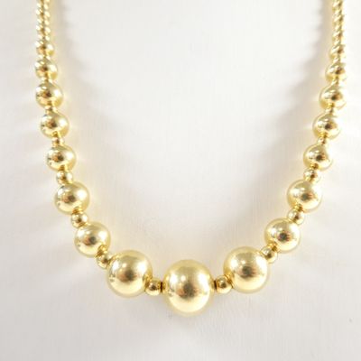un gros plan d'un collier de perles dorées sur un mannequin