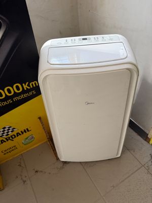 un petit climatiseur blanc posé à côté d'un panneau