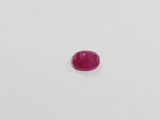 a pink oval shaped ruby stone on a white surface