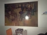 a painting on the wall above a microwave and a chair in a room