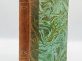 an old book with a green cover sitting on a white surface