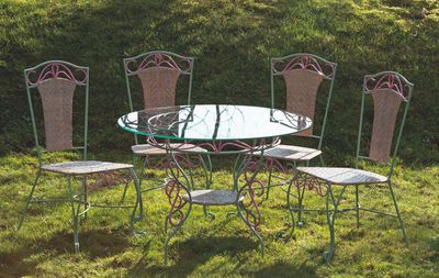 une table en verre et quatre chaises dans l'herbe