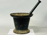 an old mortar with a pestula in it sitting on a white surface