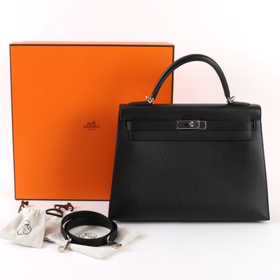 un sac à main en cuir noir posé à côté d'une boîte orange et d'une paire de lunettes