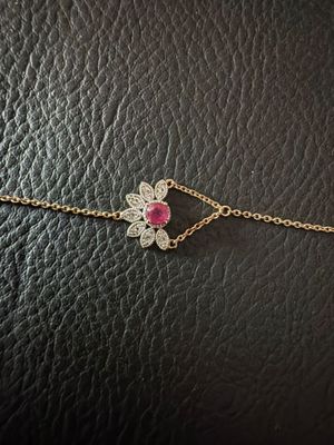 un bracelet en chaîne d'or orné d'une fleur en pierre rose