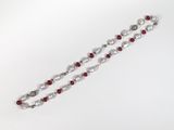 un gros plan d'un collier composé de perles blanches et rouges, posé sur une surface blanche