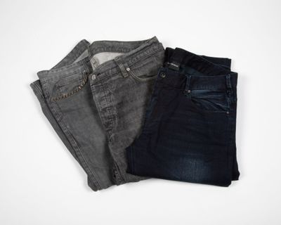 three pairs of jeans sitting on top of each other on a white surface