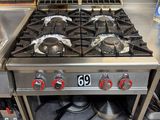 stainless steel stove top with six burners in a commercial kitchen