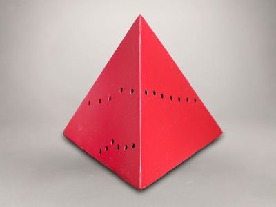 une image représentant un objet rouge en forme de pyramide, percé de trous