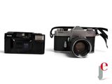 two cameras sitting next to each other on a white surface
