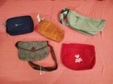 several purses are lined up on a bed with a pink blanket