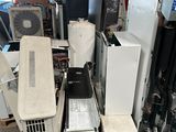 Plusieurs climatiseurs sont empilés sur des palettes dans un garage
