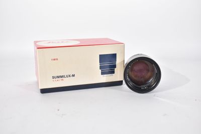 an old camera lens sitting on a white surface next to a box
