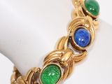 a close up of a gold bracelet with blue and green stones