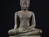 une statue en bronze représentant un Bouddha assis sur un rocher