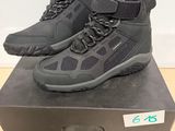 une paire de chaussures de randonnée noires posée sur une boîte