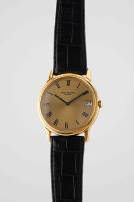 a gold plated wrist watch with roman numerals and black leather strap