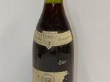 une vieille bouteille de vin posée sur une table blanche