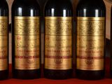 four bottles of red wine are lined up on a table