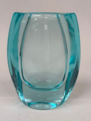 un vase en verre bleu posé sur une surface blanche