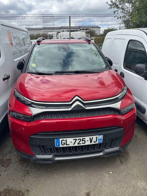 La voiture rouge est garée à côté de la camionnette blanche.