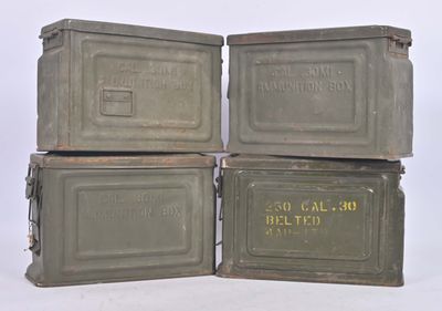 four military ammo cans stacked on top of each other on a white surface