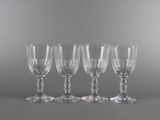 four empty wine glasses lined up on a gray surface