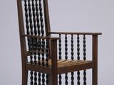 une image représentant une chaise en bois dont le dossier est orné de perles