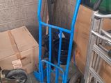 un diable bleu posé à côté d'une pile de cartons