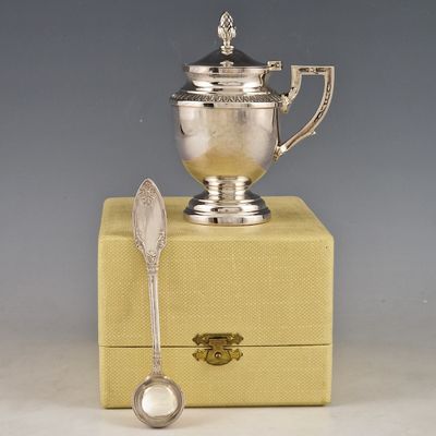 une tasse en argent posée sur une boîte, à côté d'une cuillère