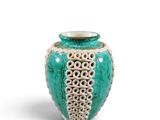 a green and white vase that is sitting on a white surface