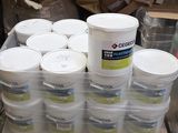 Plusieurs seaux de peinture sont empilés sur une palette dans un entrepôt