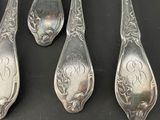 four spoons and a spoon with a monogram on them on a black surface