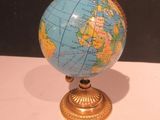 un petit globe bleu et doré posé sur une table blanche
