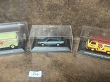 trois modèles différents de voitures sont exposés dans des boîtes transparentes posées sur une surface marron