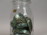 a glass jar filled with a pile of green and silver rocks