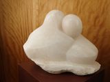 a white sculpture of a man and a woman sitting on a rock