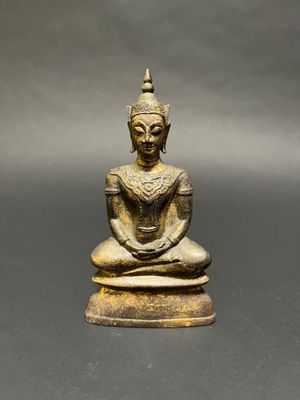 a bronze statue of a seated buddha on a black surface