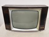 an old television sitting on top of a white table next to a white wall