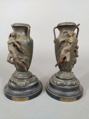 pair of antique bronze vases on marble bases on a white background