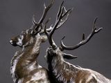bronze sculpture of two deers standing next to each other on a black background