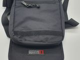 un gros plan d'un sac posé sur une surface blanche, muni d'une bandoulière noire