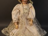 an old fashioned doll with a white dress and hat on a black background