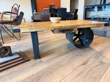 a wooden table with wheels on it in the middle of a room