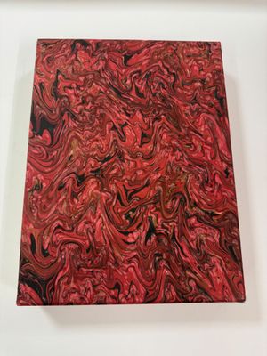 red and black marbled paper on a white surface with a white frame