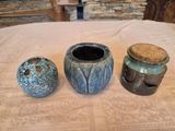 three vases sitting on a table with a stone wall in the background