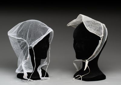 deux têtes de mannequin recouvertes de voiles blancs posées sur une tête de mannequin noire