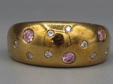 an image of a close up of a gold ring with pink and white diamonds