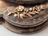 a close up of a gold plate with a flower brooch on it